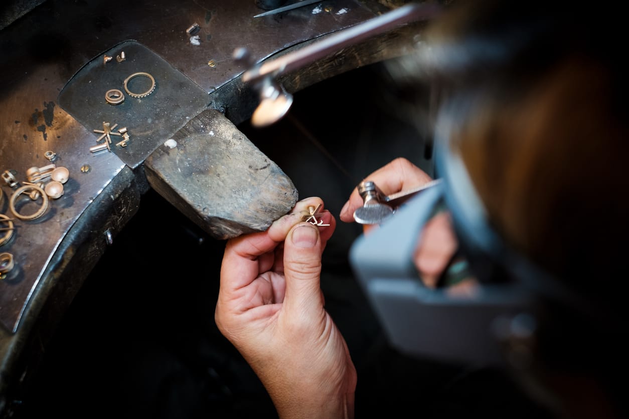 jeweler saws at a gold ring in authentic jewellery workshop Client Services